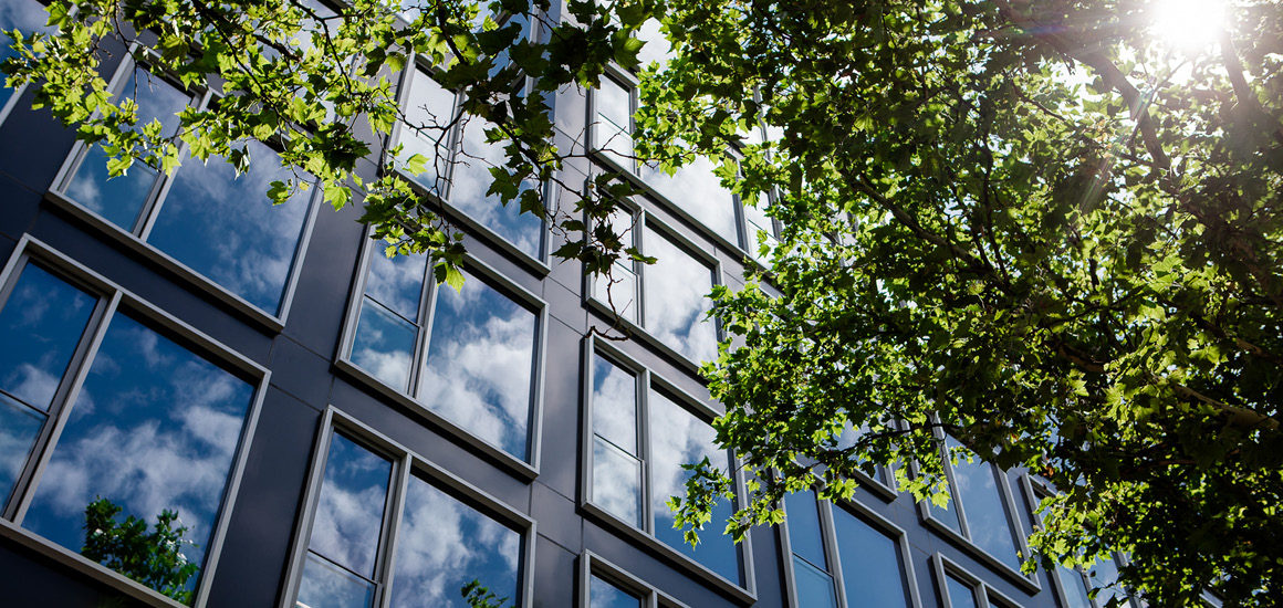Das Bild zeigt das HME-Bürogebäude mit Spiegelungen in der Fensterfassade.